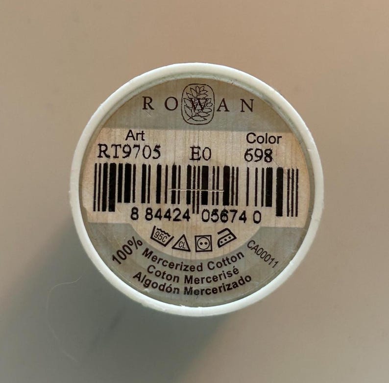 May include: A spool of Rowan mercerized cotton thread. The label displays the brand name, product details, and a barcode. The color is 698. The thread is 100% mercerized cotton.