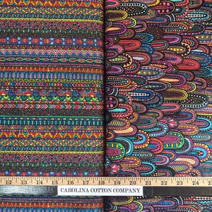 Puede incluir: Dos rollos de tela colorida con intrincados patrones geométricos. Uno presenta bandas horizontales de varios diseños en colores vibrantes, mientras que el otro tiene un patrón orgánico en capas en tonos de morado, naranja y azul. El texto "CAROLINA COTTON COMPANY" es visible.