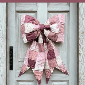 Peut inclure: Un grand nœud matelassé en tissu patchwork aux tons rose, mauve et blanc avec des motifs floraux. Le texte indique : THE BIG GIANT QUILTED BOW, Designed to be reversible, Scrappy and fat quarter friendly, 3 style options included, A beginner-friendly sewing pattern + video tutorial by: LGC LINDSEY GRACE CREATES.