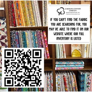 May include: Shelves filled with colorful fabric rolls and stacks. The image includes a QR code and a sign that reads "CAROLINA COTTON COMPANY" and "IF YOU CAN'T FIND THE FABRIC YOU ARE SEARCHING FOR, YOU MAY BE ABLE TO FIND IT ON OUR WEBSITE WHERE OUR FULL INVENTORY IS LISTED."