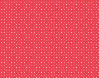 May include: A red fabric featuring a repeating pattern of small white polka dots. At the bottom edge, a white ruler is visible, showing measurements in inches from 0 to 12, with the text Riley Blake Designs printed along the scale.