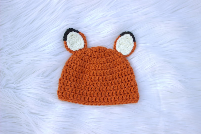 May include: Orange crocheted hat with white and black fox ears.