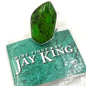 May include: A green gemstone ring with a silver band. The ring is on a card that says "Mine Finds by Jay King".