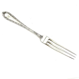 May include: A silver fork with a decorative handle. The fork has three tines and a long, slender handle.