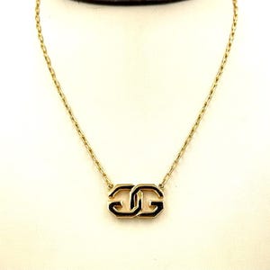 Puede incluir: Un collar de cadena de oro con un colgante doble GG de esmalte negro.