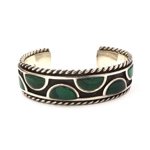 May include: A silver bracelet with a rope-like design around the edge and a row of green malachite stones set in the centre.