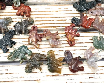 May include: A strand of gemstone elephant beads, each carved from a different type of agate. The beads are strung on a wire and are a variety of colors, including green, brown, red, and white.