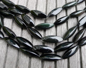 May include: A strand of black and green gemstone beads, each bead is oval shaped and polished.
