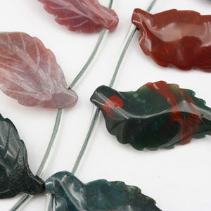 May include: A strand of gemstone beads in the shape of leaves. The leaves are carved from green, red, and pink agate. The beads are strung on silver wire.