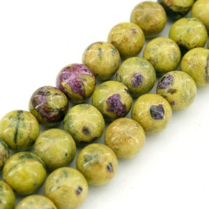 May include: A strand of round, green and purple gemstone beads. The beads have a mottled, speckled appearance.