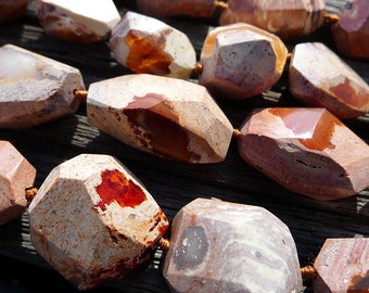 May include: A strand of faceted, irregularly shaped, brown, white, and red gemstone beads. The beads are polished and have a natural, earthy look.