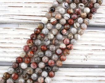 May include: A strand of round, brown, white, and red agate beads. The beads have a natural, marbled pattern.