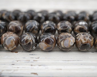 May include: A strand of brown and white agate beads with a swirling pattern. The beads are round and smooth.