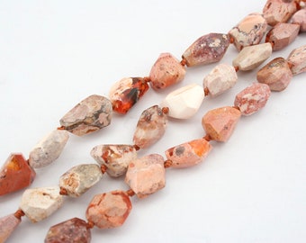 May include: A strand of natural stone beads with a mix of brown, pink, and white colors. The beads are irregularly shaped and have a rough, textured surface.