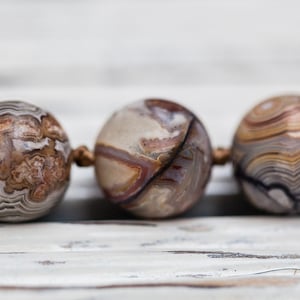 May include: Close-up of a necklace made of brown, white, and black agate beads. The beads have a swirling, marbled pattern.