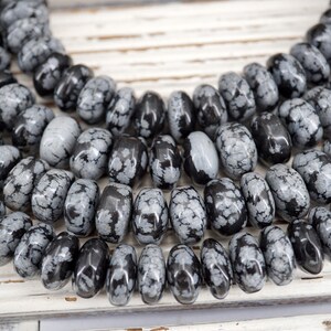 Puede incluir: Una hebra de cuentas de piedra preciosa moteada de negro y blanco. Las cuentas son de forma ovalada y tienen un acabado liso y pulido.