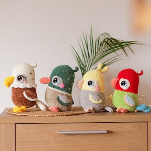 May include: Four crocheted stuffed animals in the shape of birds. The birds are an eagle, a duck, a parakeet, and a parrot. The eagle is brown and white, the duck is green and white, the parakeet is yellow and gray, and the parrot is red and green.