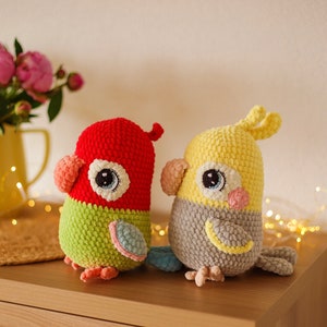 May include: Two crocheted stuffed birds, one red and green and the other yellow and gray, with large eyes and beaks.