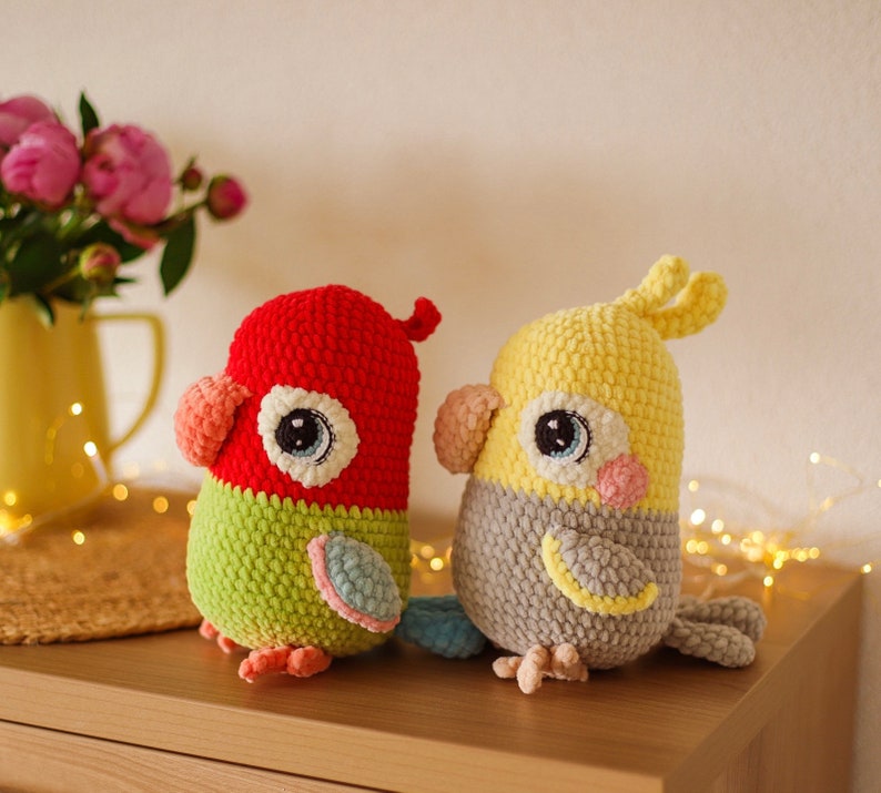May include: Two crocheted stuffed birds, one red and green and the other yellow and gray, with large eyes and beaks.