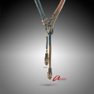 以下が含まれることがあります： 中央に結び目があり、3つのビーズの雫がぶら下がっている長いビーズネックレス。ネックレスは黒、茶色、緑のビーズで作られています。