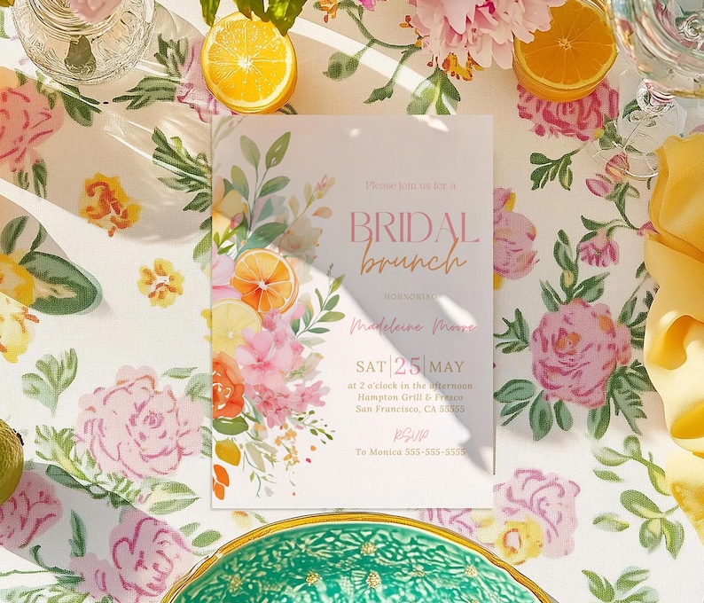 Floral citrus bridal brunch invitation featuring watercolor oranges, lemons, pink blooms, and soft greenery along the side with blush, coral, and gold text. The design includes bridal brunch wording with event details and RSVP section in elegant script and serif fonts. Styled flat on a floral tablecloth with fresh citrus slices, glassware, and a yellow napkin, creating a bright spring and summer tablescape.