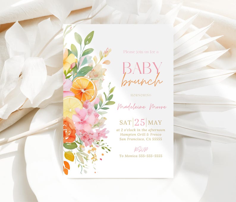 Watercolor floral citrus baby brunch invitation featuring pink blossoms oranges and greenery with elegant event text. The layout is minimal with strong focus on the left floral cluster and airy spacing. Card rests on layered neutral botanical textures with soft dried leaves surrounding it. Light and shadow create depth and a styled editorial feel.