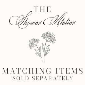 May include: Cream-colored graphic with the text "THE Shower Atelier" in elegant script above a floral illustration. Below, the text reads "MATCHING ITEMS SOLD SEPARATELY" in a serif font. The design is simple and elegant.