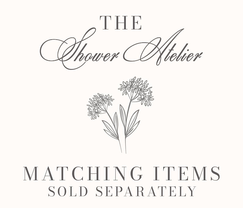 May include: Cream-colored graphic with the text "THE Shower Atelier" in elegant script above a floral illustration. Below, the text reads "MATCHING ITEMS SOLD SEPARATELY" in a serif font. The design is simple and elegant.