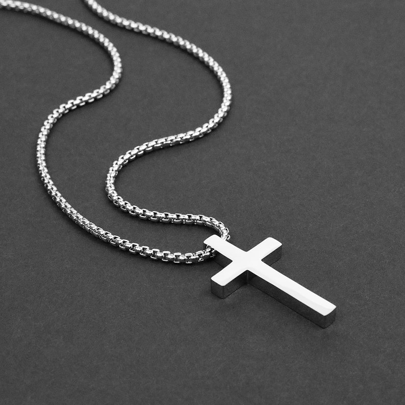 May include: A silver chain necklace with a silver cross pendant.