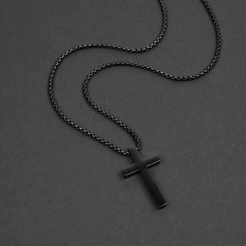 May include: A black chain necklace with a black cross pendant.