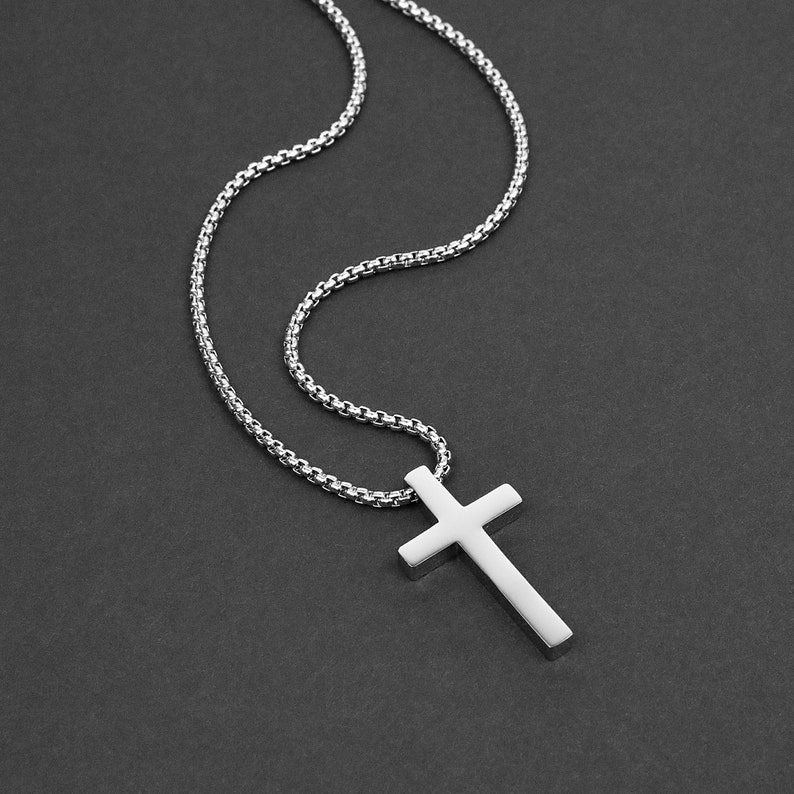 May include: A silver chain necklace with a silver cross pendant.