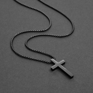 May include: A black chain necklace with a black cross pendant.