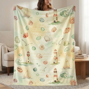 May include: A soft, cream-colored blanket featuring a nautical design. The pattern includes watercolor illustrations of sailboats, lighthouses, seashells, and seagulls. The blanket has a vintage aesthetic with a faded, handwritten script background.