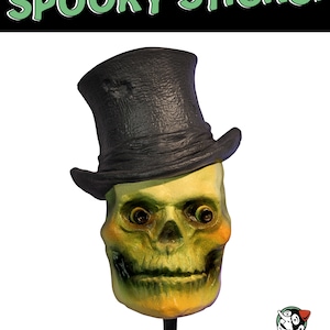 Peut inclure: Un crâne vert et jaune portant un chapeau haut de forme noir avec le texte "MR. BONES" et "SPOOKY STICKS!" sur l'image.
