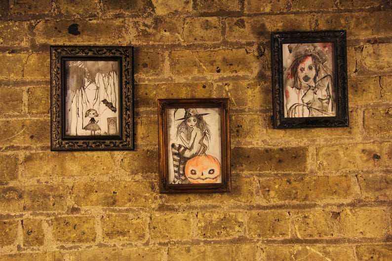 Peut inclure: Trois dessins en noir et blanc encadr&eacute;s sur un mur de briques. Les dessins repr&eacute;sentent une femme avec une citrouille, une femme avec un chapeau et une femme avec un oiseau.