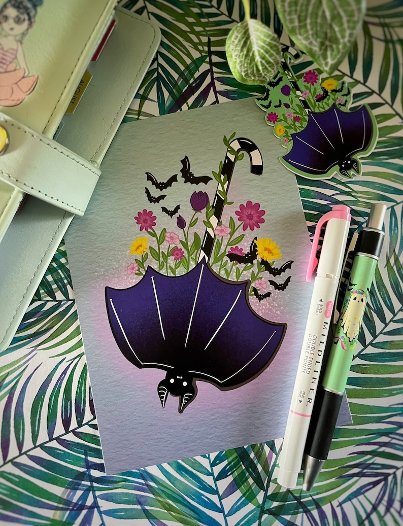 May include: A purple bat with a candy cane stem and flowers in a purple umbrella. The bat has a cute face and is surrounded by bats flying in the air. The background is a light blue gradient.