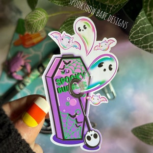 May include: A purple and green coffin-shaped sticker with the text "Spooky Bubbles" and a ghost blowing bubbles. The sticker features a spiderweb design and bats.