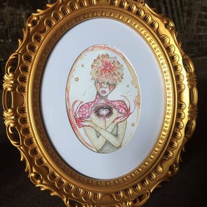 May include: A watercolour painting of a person with a flower head and an eye in their chest. The painting is framed in a gold oval frame.