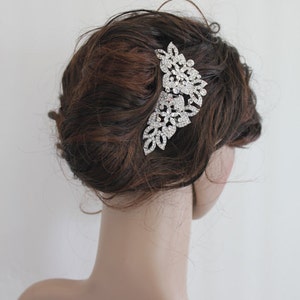 May include: Silver hair comb with a large, ornate design featuring clear rhinestones. The comb is shown in a model's hair.