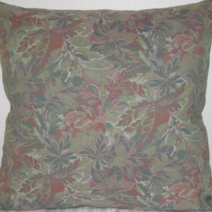 May include: A decorative throw pillow with a green, pink, and brown floral pattern. The pillow is made of a soft, textured fabric.