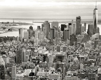 May include: A black and white aerial view of a city skyline with tall buildings and a wide street in the foreground. The Flatiron Building is visible in the center of the image.