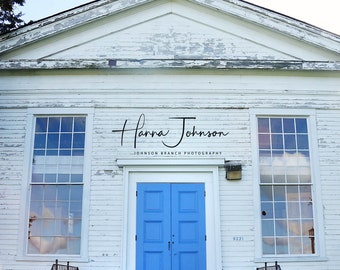 May include: A white church with a blue door and a steeple. The church is weathered and has peeling paint. The door has a simple design with four panels. The church is surrounded by green grass.