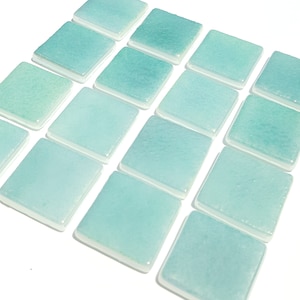 May include: A collection of square, seafoam-colored glass tiles with a glossy finish. Each tile has a slightly irregular surface and a white border, arranged in a grid pattern against a white background. The tiles vary slightly in shade.