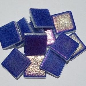 May include: A collection of iridescent blue and purple glass mosaic tiles. The tiles are square shaped and have a textured surface.