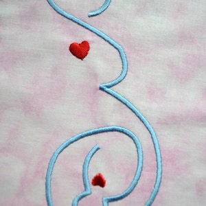 May include: Embroidered light blue letter "S" with two red hearts on a pink and white fabric background. The design is stitched with a satin stitch. The text "THERE'S AN APPLIQUE FOR THAT" is at the bottom.