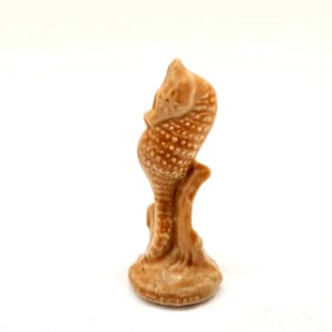May include: A light brown ceramic seahorse ornament. The seahorse has a textured surface with small, raised dots and is mounted on a small base. The figurine is a decorative item.