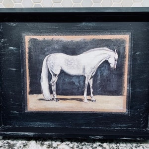 May include: A black wooden tray with a white horse illustration in a beige frame. The horse is standing on a beige background with a dark blue background behind it.