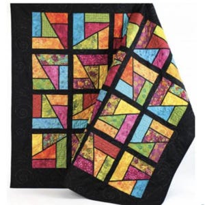 May include: A colorful quilt with a stained glass window design. The quilt is made up of squares of different colors and patterns, including red, orange, yellow, green, blue, and purple. The quilt is folded in half, and the edges are trimmed with black fabric.