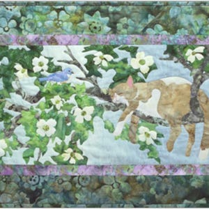 May include: A rectangular quilt featuring a cat resting on a tree branch, surrounded by white flowers and blue birds. The quilt has a floral border in shades of green and purple, creating a serene, nature-inspired scene.