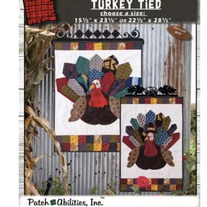 May include: A fabric wall hanging with a turkey design. The turkey has a red head and a brown body, with colorful patchwork feathers. The text "TURKEY TIED" is at the top, with size options of 15.5" x 23.5" or 22.5" x 28.5".